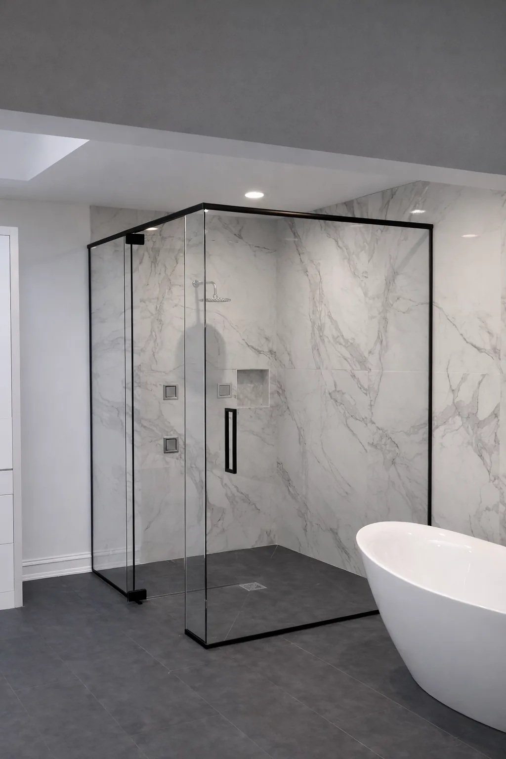 Clear corner shower with slim black perimeter framing, dark hardware and marble-patterned wall tile.
