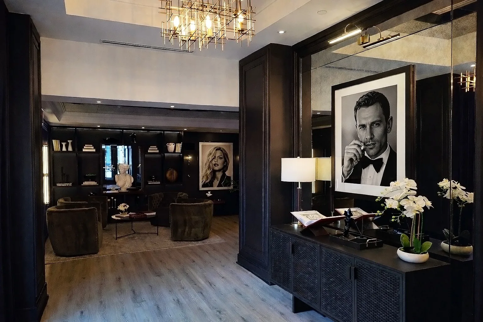 Large mirror panels behind framed artwork and a console in a dark wood lounge.