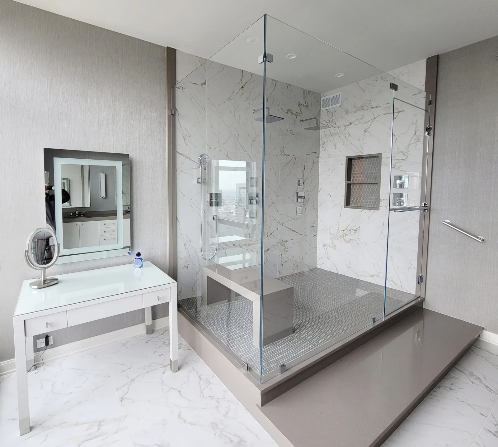 Frameless corner shower on a tiled platform with a built-in bench and a white vanity alongside.