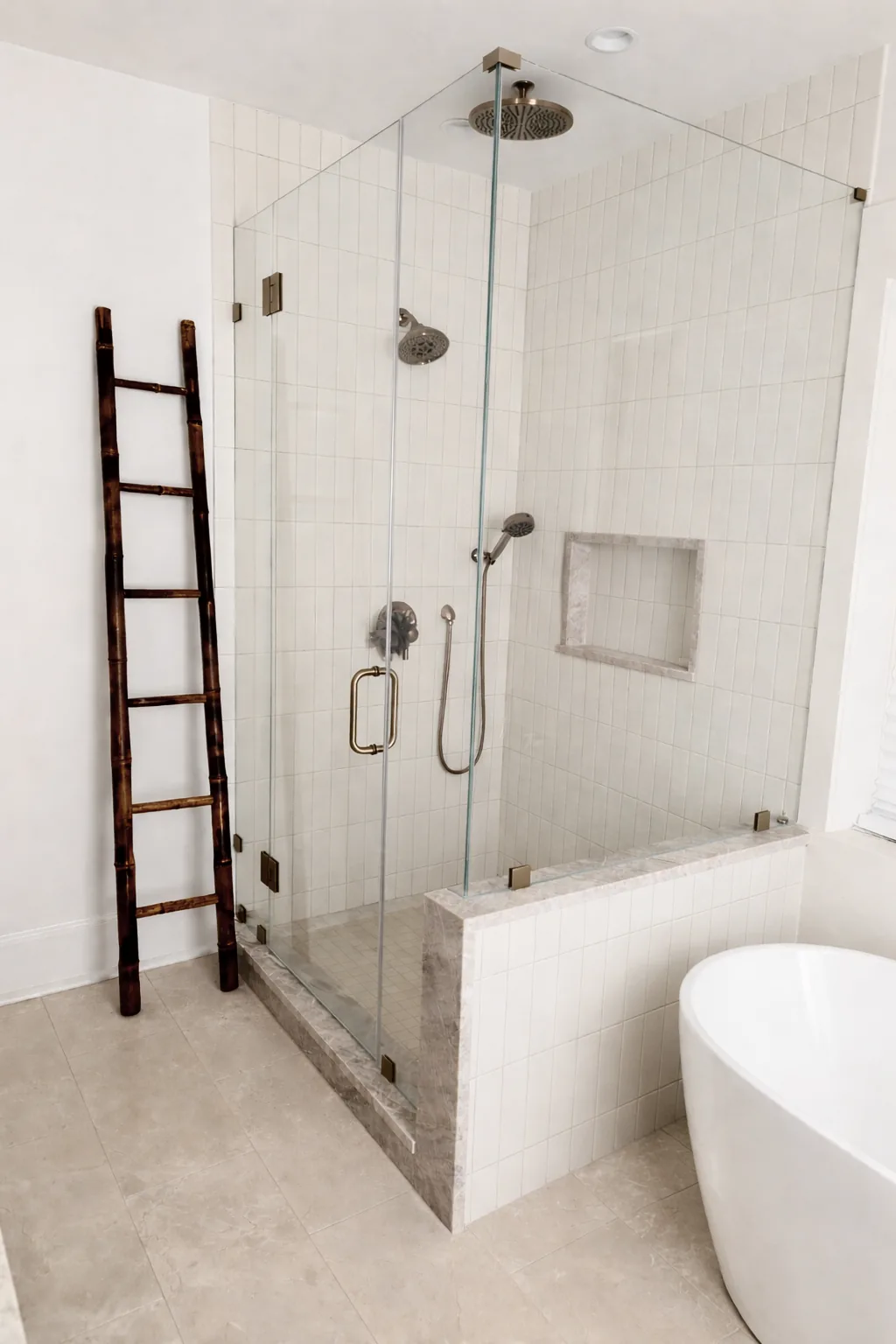 Clear corner shower with warm metal hinges and pulls, white wall tile and a tiled knee wall.